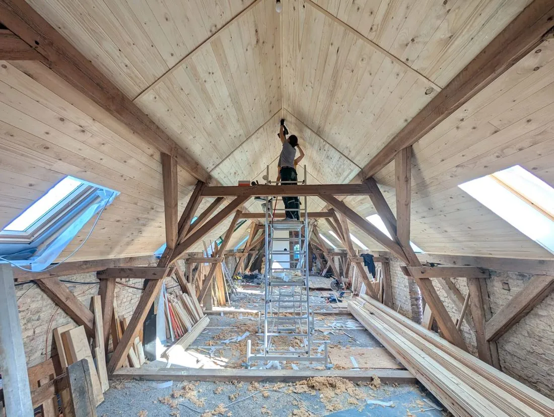 Das Dachgeschoss während des Umbaus: frische Holzverkleidung, Gerüst und Bretter auf dem Boden