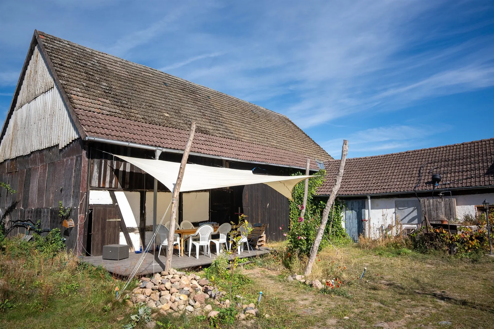 Die Holzterrasse vor der Fachwerkscheune mit Sonnensegel und Sitzgruppe